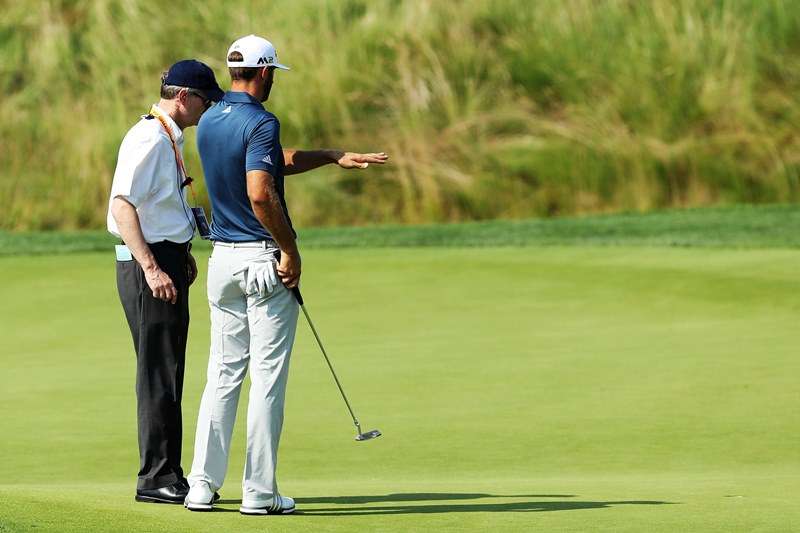 Head shaker: Dustin Johnson talks to the official on the green at the 5th (photo by Getty Images)